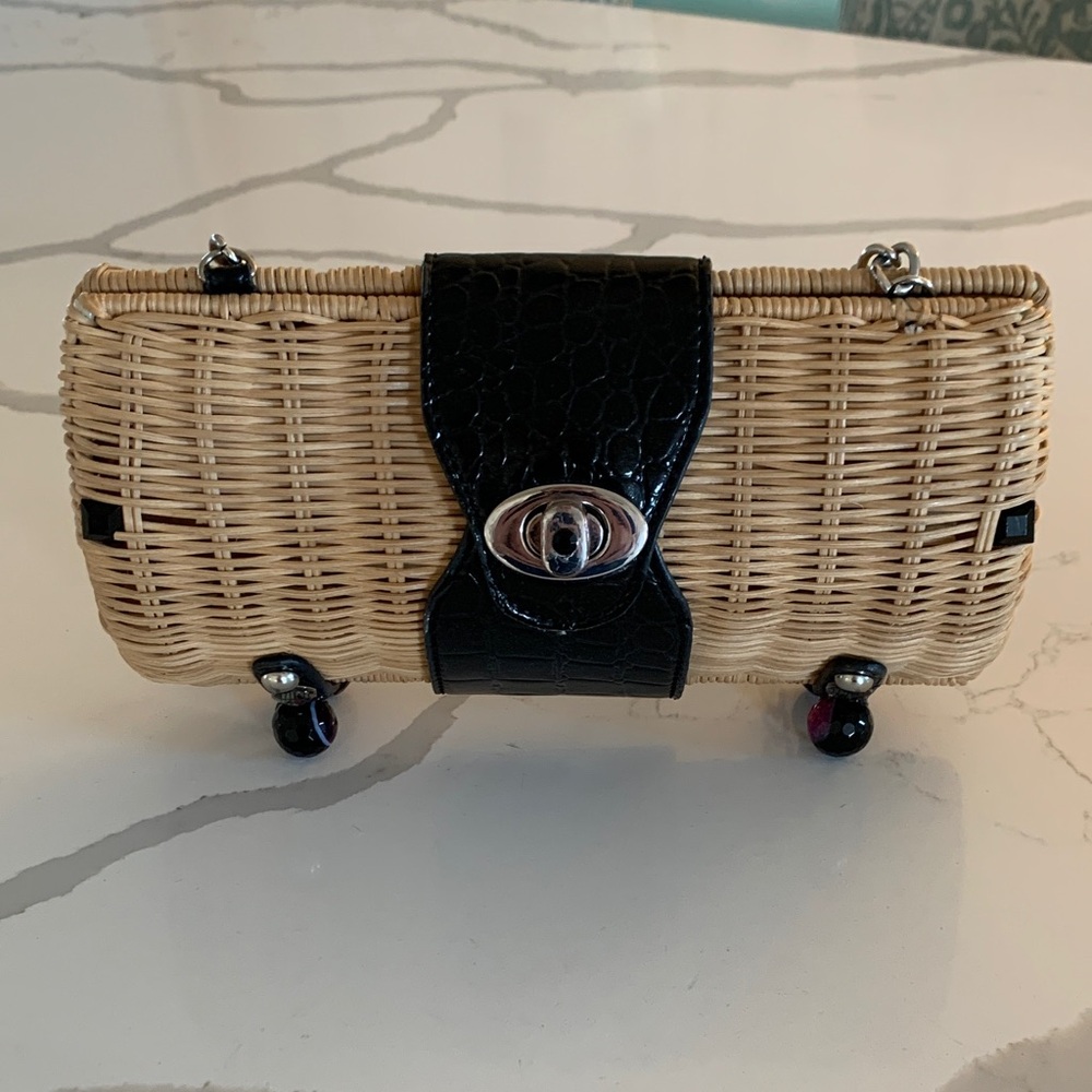 Wicker purse with chain strap, and designed feet on the bottom.